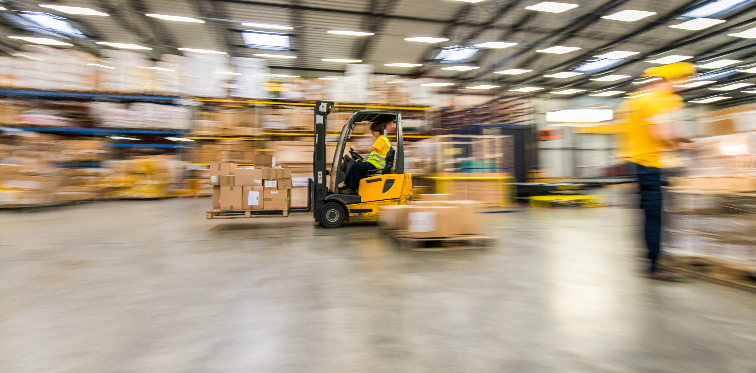 Panning Shot Of Moving Forklift In A Warehouse